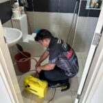 Technician using equipment to clean a bathroom floor, ERZ Teguh Aircond Service, Petaling Jaya
