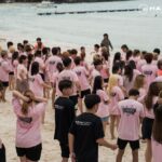 Large group in matching shirts gathered on beach, Hairstory International, George Town