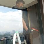 Worker cleaning a high-rise window with squeegee, Idealife cleaning service, Petaling Jaya