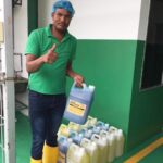 Worker holding chemical container beside packed jugs, Joywash Marketing, Johor Bahru
