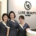 Three staff in uniform posing at reception desk, Luxe Beauty Retreat, Petaling