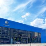 Blue car dealership showroom building under bright sky, Proton Atiara Johan Body and Paint Center, Puchong