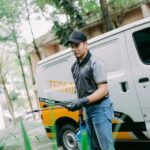 Worker spraying pesticide beside company van, Termibait Facility Services Sdn. Bhd, Subang Jaya